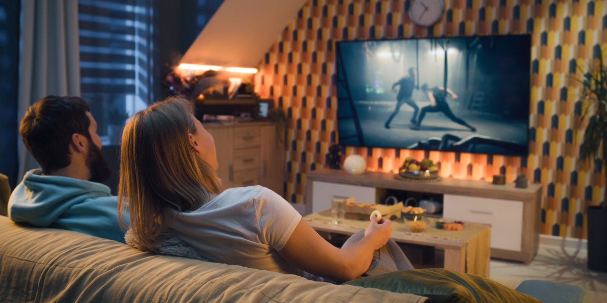 two people watching on a large TV